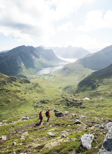 Foto gratuita vertical de personas caminando en las montañas de las islas lofoten en un clima nublado