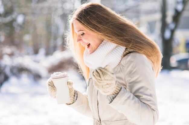 Veterinario de sexo femenino feliz que sostiene la taza de café para llevar que se coloca en nieve