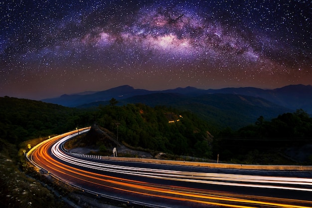 Vía Láctea y luz del coche en la carretera en el parque nacional Doi Inthanon en la noche, Chiang Mai, Tailandia.