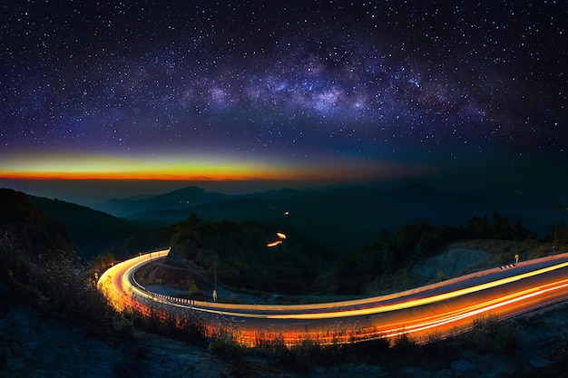 Vía Láctea y luz del coche en la carretera en el parque nacional Doi Inthanon en la noche, Chiang Mai, Tailandia.