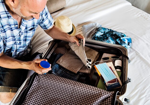 Viaja en la nueva normalidad, hombre empacando una maleta