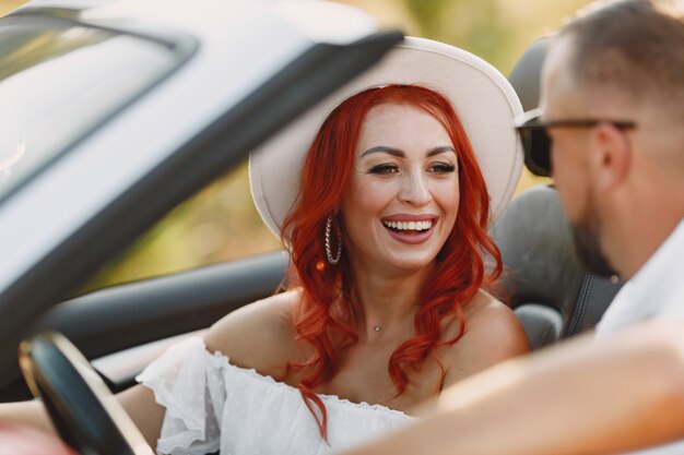 Viaje familiar feliz en coche por las montañas. Gente divirtiéndose en cabriolet rojo. Concepto de vacaciones de verano