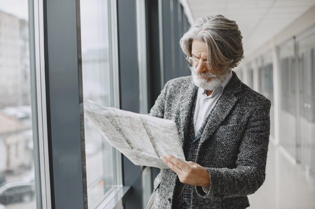 Viaje de negocios. Concepto corporativo y personas. Hombre con un abrigo gris. Senior con un mapa.