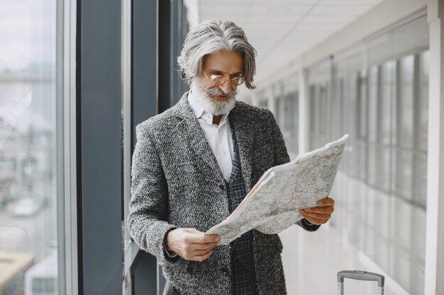 Viaje de negocios. Concepto corporativo y personas. Hombre con un abrigo gris. Senior con un mapa.