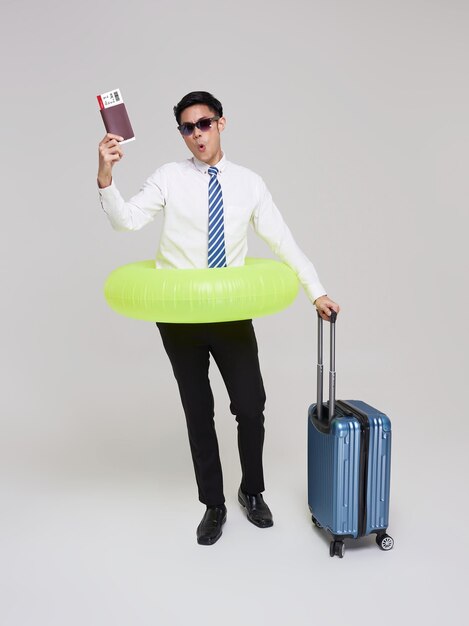 viaje verano empresario asiático mostrando billete de avión con equipaje y anillo inflable de natación