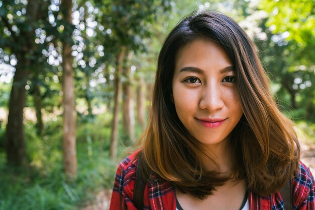 Viajero asiático joven feliz de la mujer con la mochila que camina en bosque.