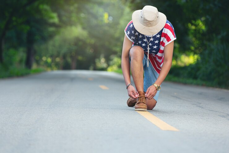 Foto gratuito un viajero se ata los zapatos en un camino rural.
