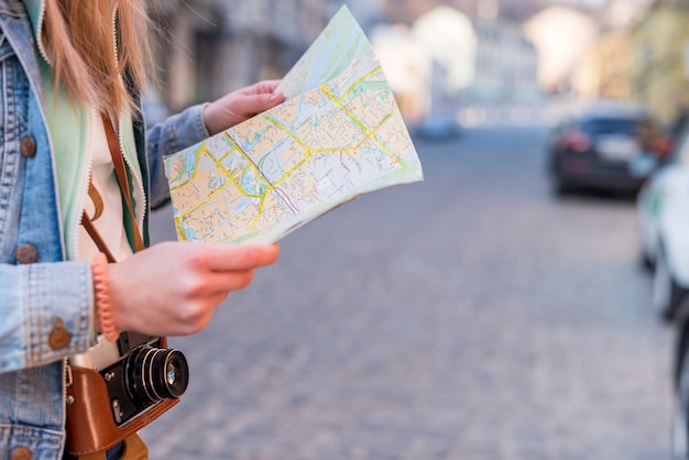 Viajero femenino buscando la dirección en el mapa de ubicación en el centro de la ciudad