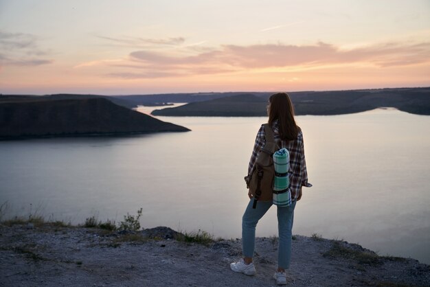 Viajero femenino con mochila de pie en la colina en la bahía de bakota