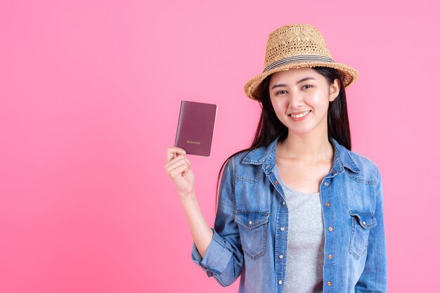 Viajero femenino con sombrero de traw tiene pasaporte Retrato de muy sonriente adolescente feliz en rosa