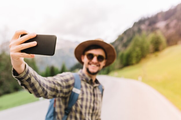 Viajero guapo posando en el paisaje de la naturaleza italiana y sonriendo, disfrutando de unas vacaciones activas