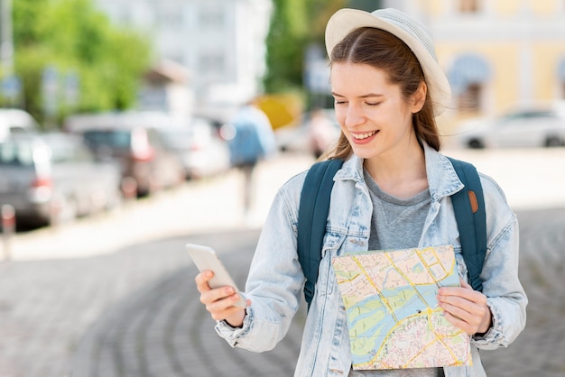 Viajero con mapa y tiro medio de teléfono móvil