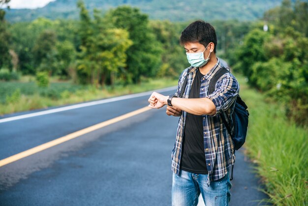 Un viajero masculino con una bandolera y mirando su reloj.