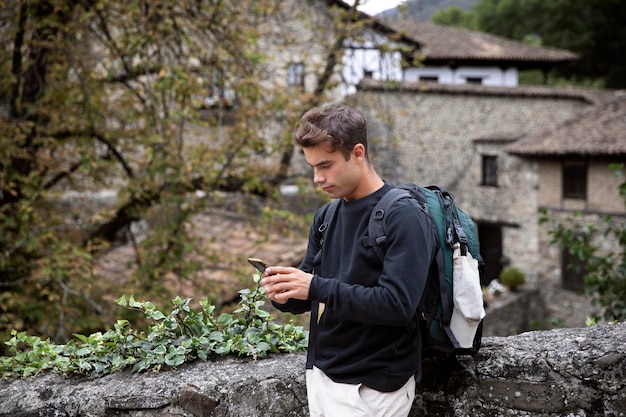 Foto gratuita viajero masculino joven que controla su teléfono inteligente