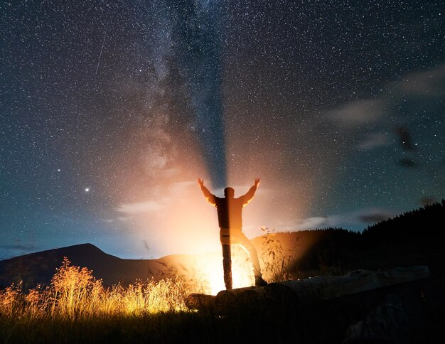 Viajero masculino parado bajo un hermoso cielo nocturno con estrellas