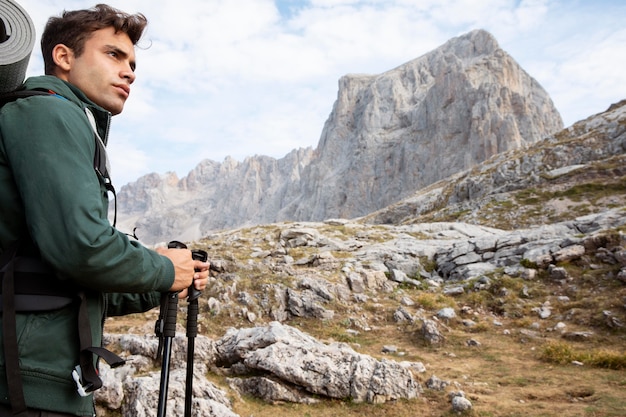 Viajero masculino senderismo en las montañas mientras tiene sus elementos esenciales en una mochila