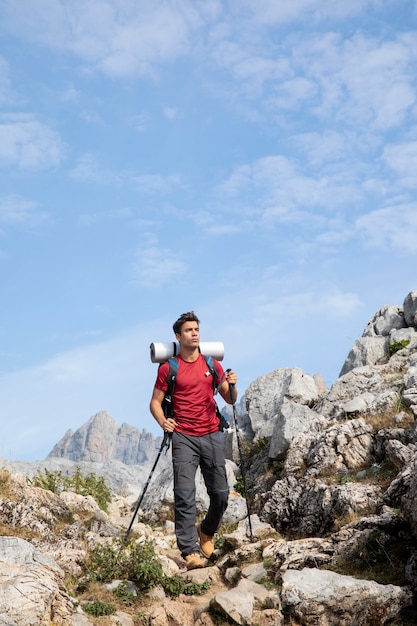 Viajero masculino senderismo en las montañas mientras tiene sus elementos esenciales en una mochila