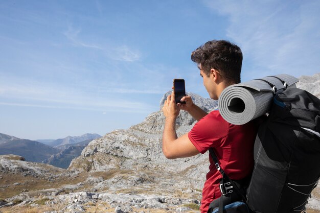 Viajero masculino senderismo en las montañas mientras tiene sus elementos esenciales en una mochila