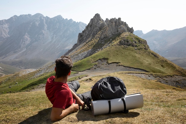 Viajero masculino senderismo en las montañas mientras tiene sus elementos esenciales en una mochila