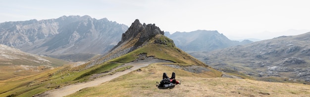 Viajero masculino senderismo en las montañas mientras tiene sus elementos esenciales en una mochila