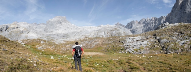 Viajero masculino senderismo en las montañas mientras tiene sus elementos esenciales en una mochila