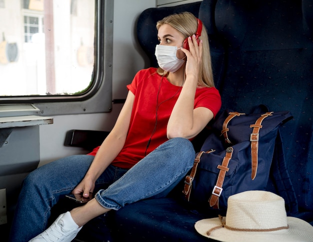 Viajero mujer con máscara escuchando música