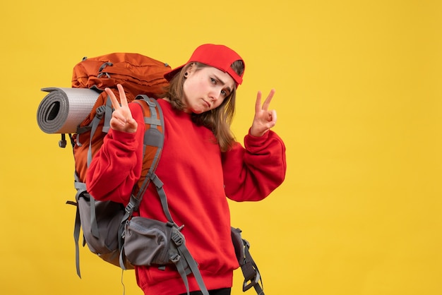 Viajero mujer vista frontal con mochila gesticulando el signo de la victoria