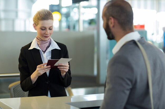 Viajero de pie en el mostrador mientras el asistente revisa su pasaporte