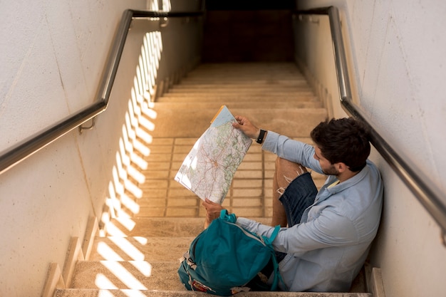 Foto gratuita viajero sentado en las escaleras y mirando en el mapa