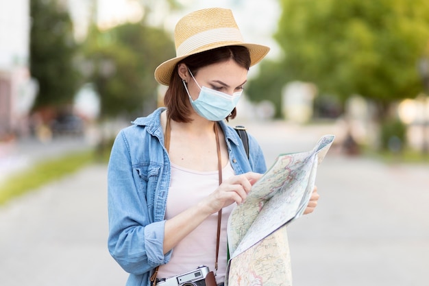 Foto gratuita viajero con sombrero y máscara de comprobación de mapa