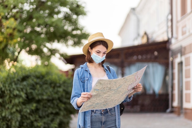 Viajero con sombrero y máscara médica comprobando el mapa