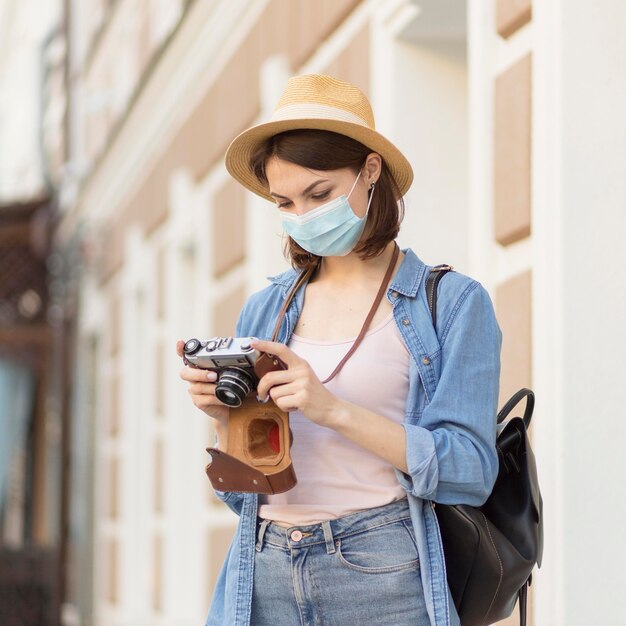 Viajero con sombrero y máscara médica revisando fotos