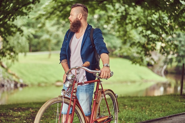 Un viajero vestido con ropa informal con una mochila, relajándose en un parque de la ciudad después de andar en bicicleta retro.