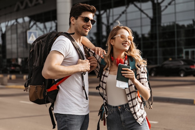 Viajeros con mochilas posa cerca del aeropuerto moderno