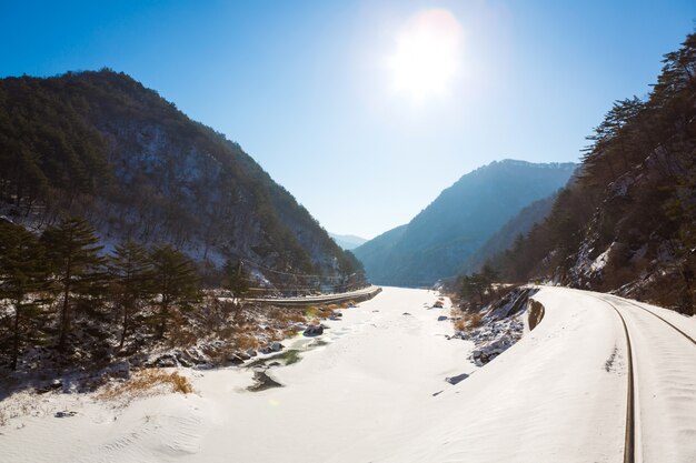 Vías del tren a través de la nieve del invierno con la luz del sol