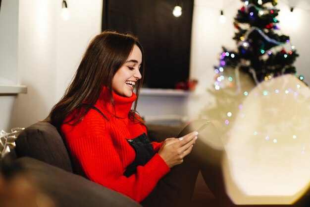 Vibes de navidad y año nuevo. Decoraciones para el hogar. Encantadora joven en suéter rojo