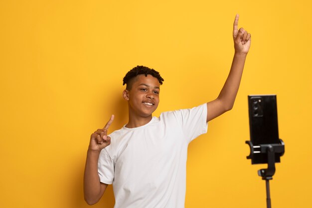 Foto gratuita video de grabación de adolescente sonriente de tiro medio