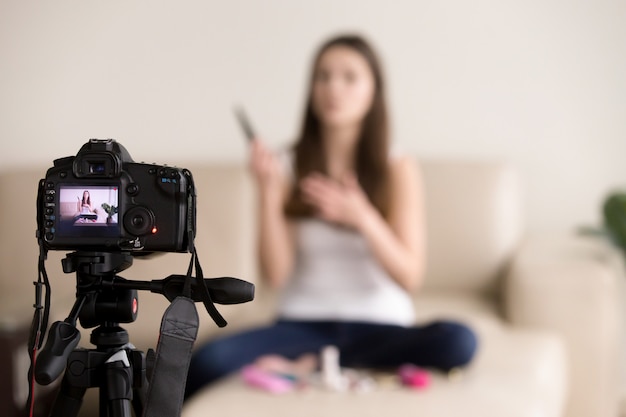 Videoblogger femenino joven que registra la revisión del producto para el blog.