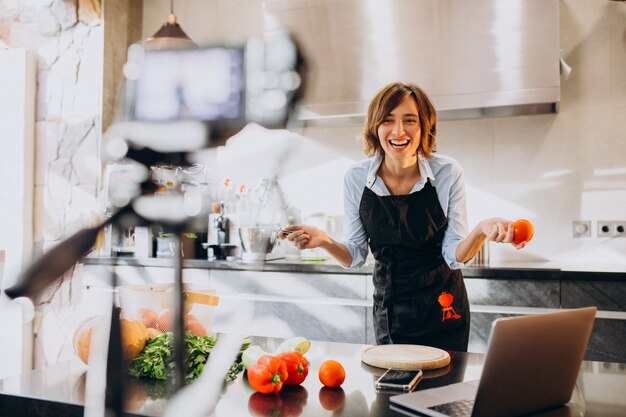 Videoblogger joven cocinando en la cocina y filmando