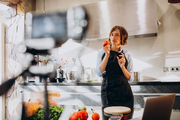 Foto gratuita videoblogger joven cocinando en la cocina y filmando