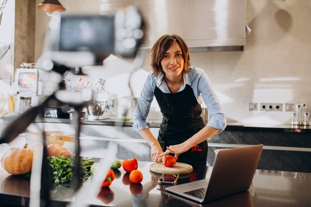 Videoblogger joven cocinando en la cocina y filmando