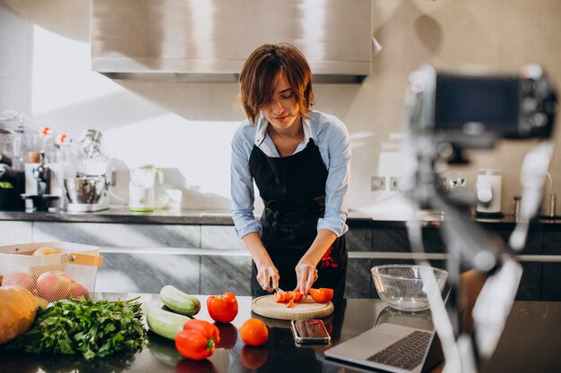 Videoblogger joven cocinando en la cocina y filmando