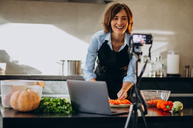 Videoblogger joven cocinando en la cocina y filmando