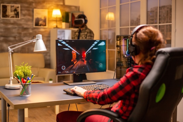 Videojugador profesional femenino jugando un juego de disparos en línea a altas horas de la noche en la sala de estar