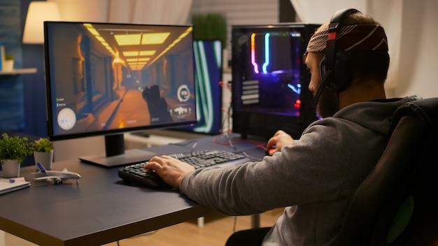 Foto gratuita videojugador que gana un torneo de disparos en primera persona con un teclado rgb y auriculares profesionales. hombre de jugador profesional hablando con otros jugadores en línea para la competencia de juegos en una computadora potente