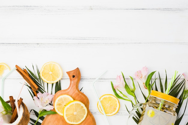 Foto gratuita vidrio cerca de las hojas de la planta con limón fresco y tabla de cortar