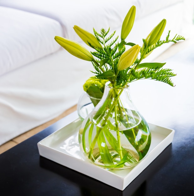 Vidrio transparente con flores verdes colocado como decoración interior en una casa