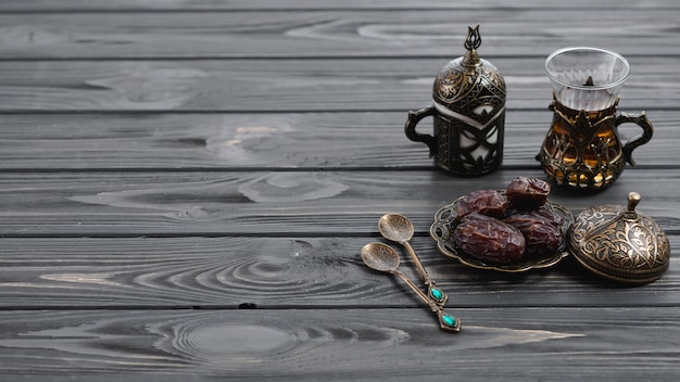 Vidrios árabes turcos tradicionales del té y fechas secadas con las cucharas en la tabla de madera