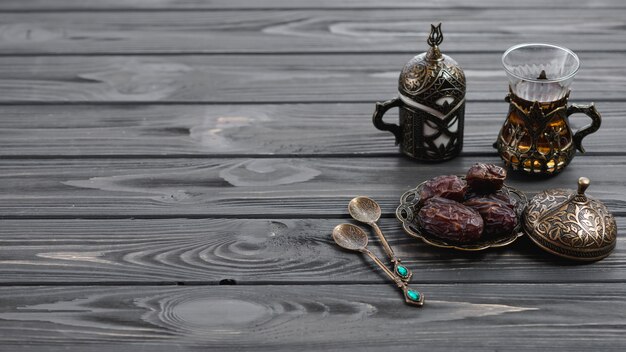 Vidrios árabes turcos tradicionales del té y fechas secadas con las cucharas en la tabla de madera
