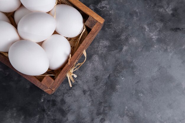 Una vieja caja de madera llena de huevos crudos de gallina blanca.